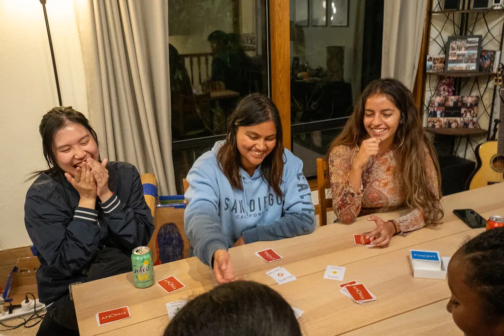 Klesis students laughing over a card game at Friendsgiving