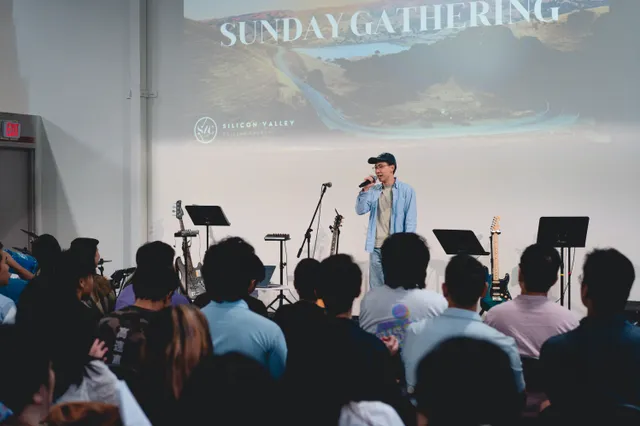 Speaker addressing the room under the Sunday Gathering title screen