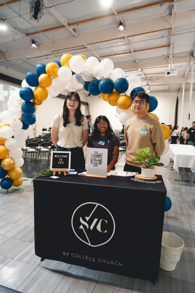 Welcome team at the SVC College Church table under a balloon arch