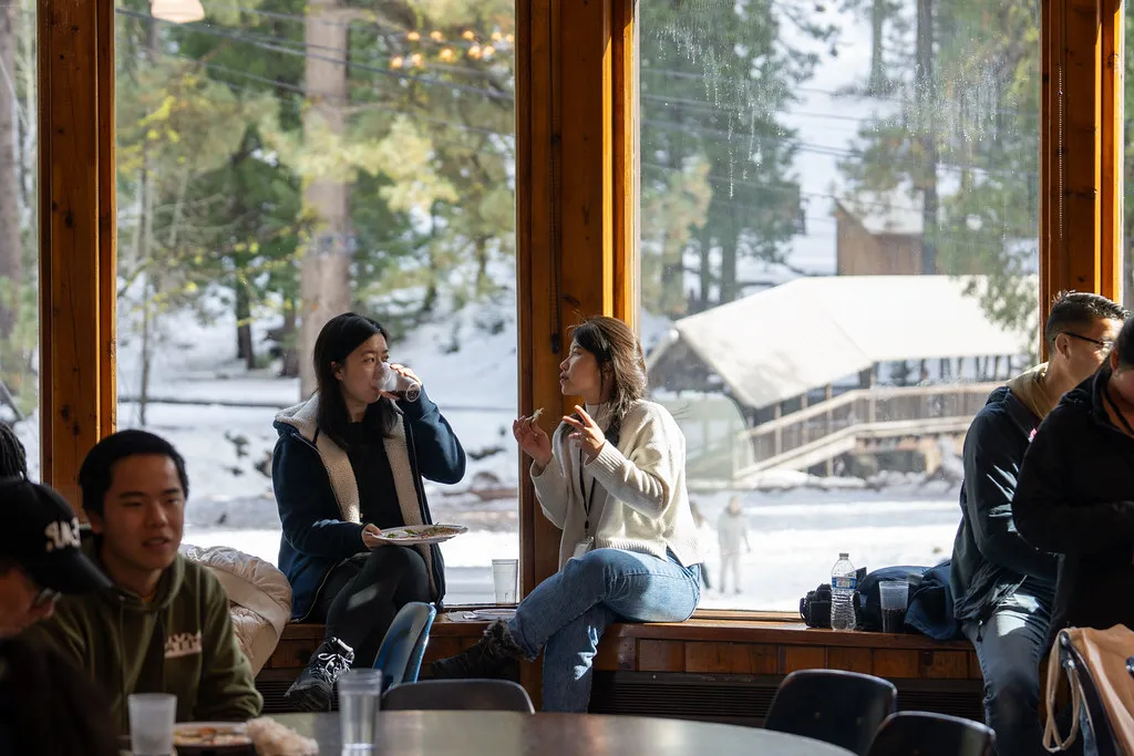 Klesis students chatting by a window overlooking the snow at the NorCal Winter Conference